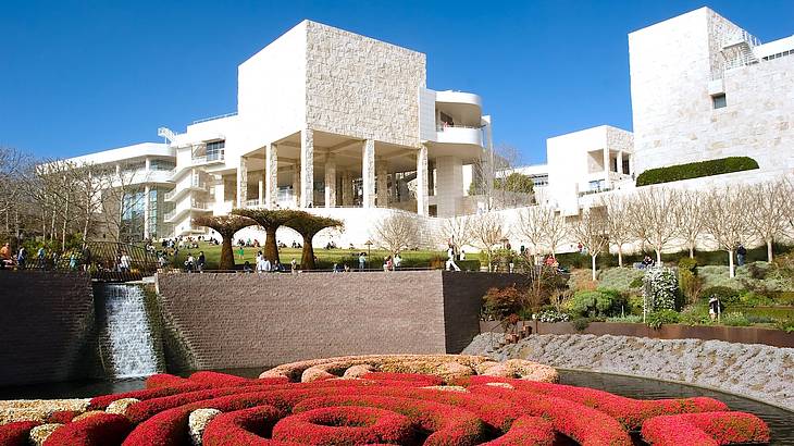 Side view of white buildings facing a garden with colourful shrubs and greenery
