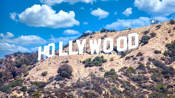 Big and white Hollywood sign on a dry mountain under a partly cloudy sky