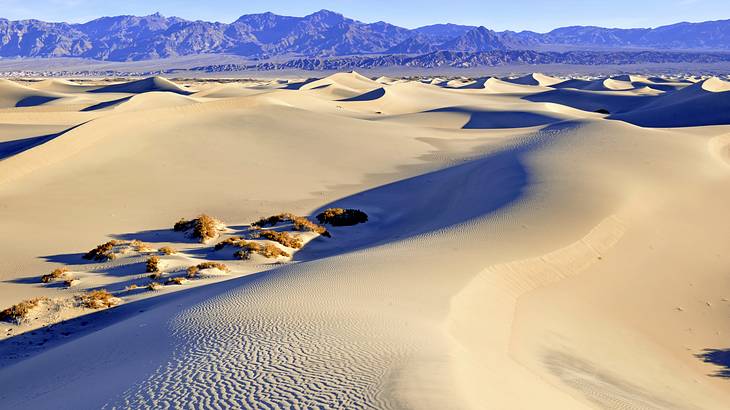 White sand dunes with rocks, with mountains in the distance