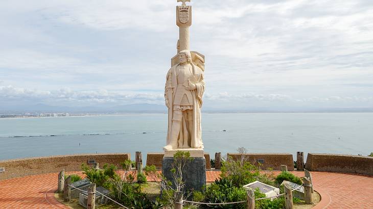 White statue overlooking the ocean with a cloudy sky in the background