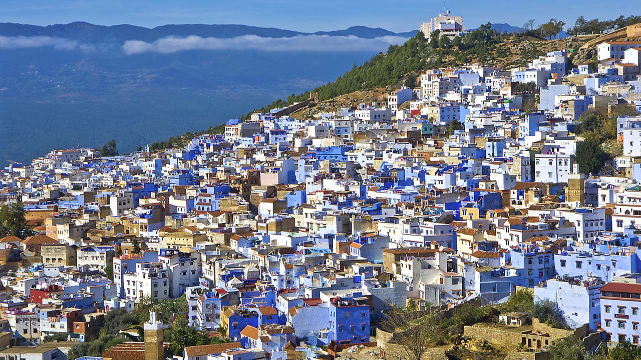 A panoramic view of white and blue houses surrounded by mountains