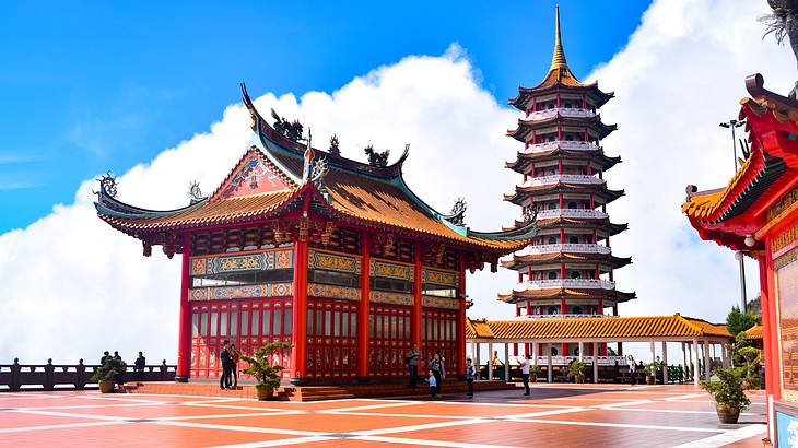 A temple and pagoda standing side by side overlooking mountains with clouds behind