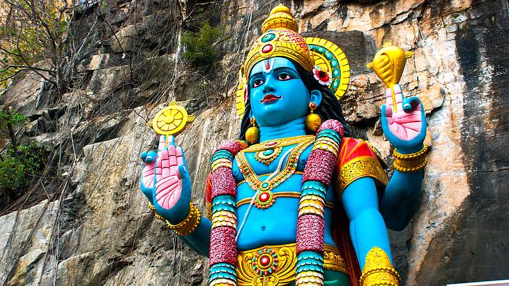 A colorful statue of a Hindu god against a rocky wall