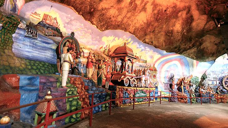 Colorful statues and figures on the rock walls inside a cave