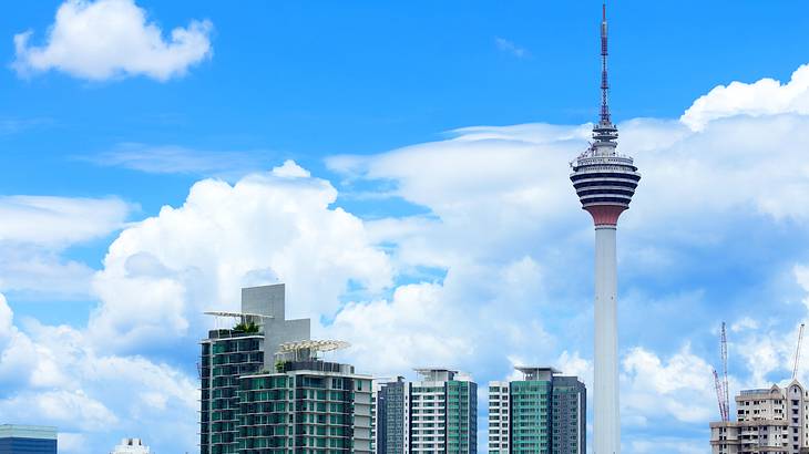 A tall tower's close-up view standing between buildings against a partly cloudy sky