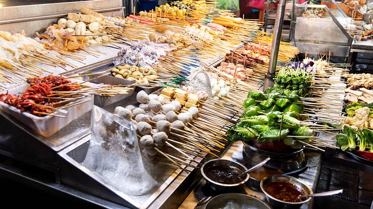 Focused image of various street foods on skewers on ice displayed in a stall