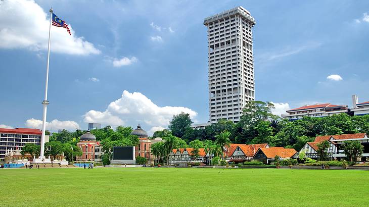 A wide green lawn with a flagpole and a tall building at the back