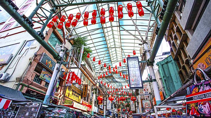 View from below of rows of shops and stalls under a canopy with red lanterns