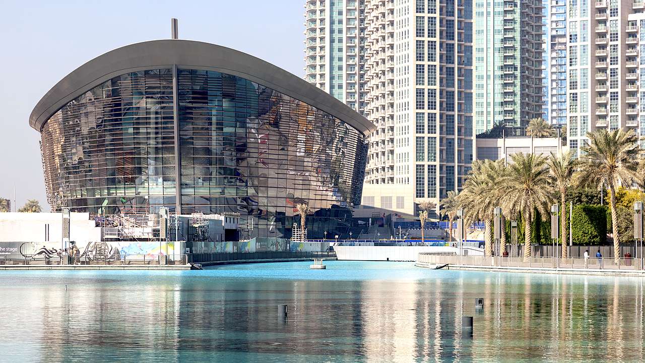 The exterior of a ship-like building facing a body of water surrounded by skyscrapers