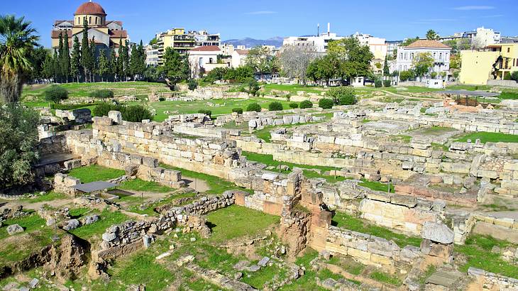 Ancient cemetery ruins from above surrounded by trees and buildings in the background