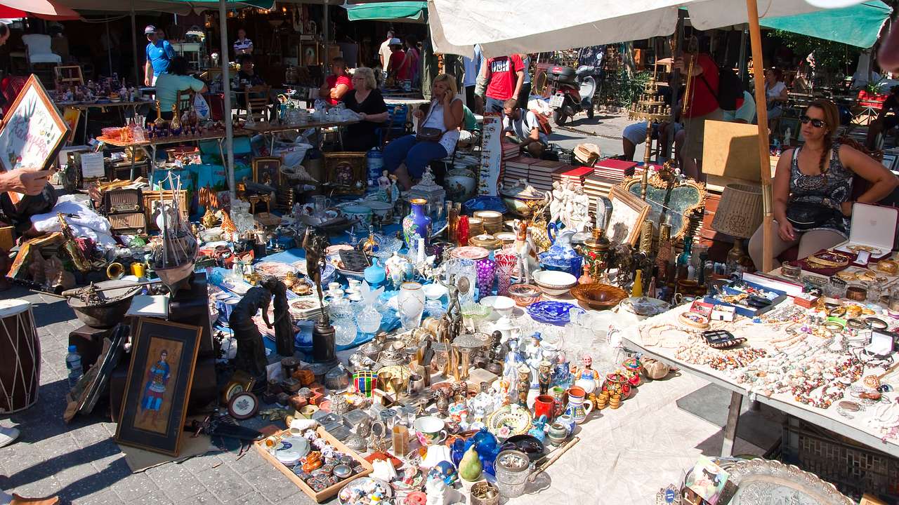 Market items, like vases, dishes, furniture, and crates, on a pavement