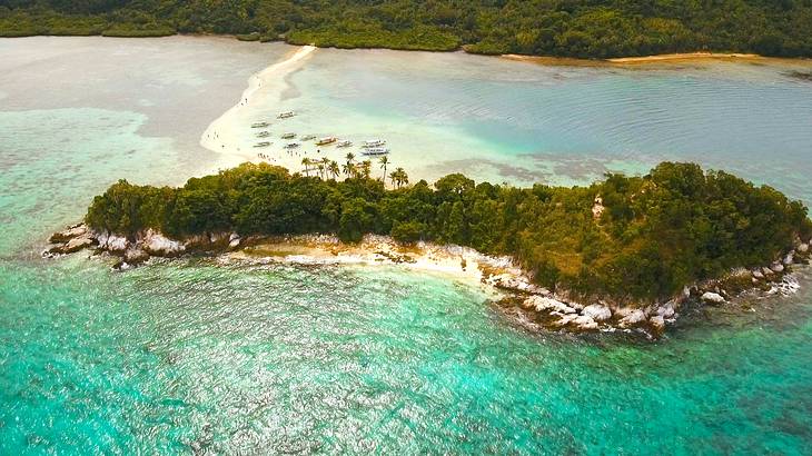 Aerial shot of a lush island connected to another island by a white sand bar