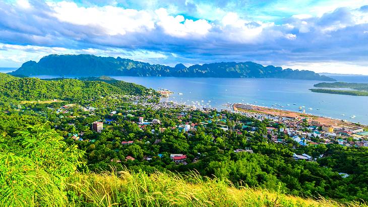 Looking down on a small town amongst greenery with water and hills at the back