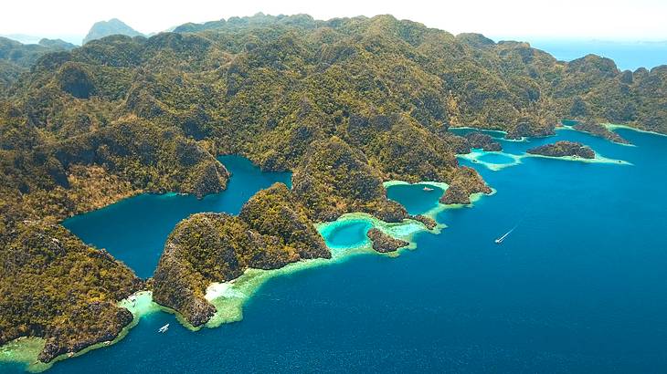 Aerial view of a deep blue lake amongst tall limestone rocks with greenery