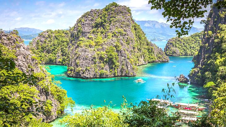 A very blue lake surrounded by tall rocks and boats on the right