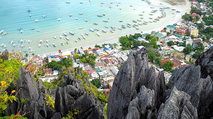 View of a town, trees, and blue water below from a cliff up high on a nice day