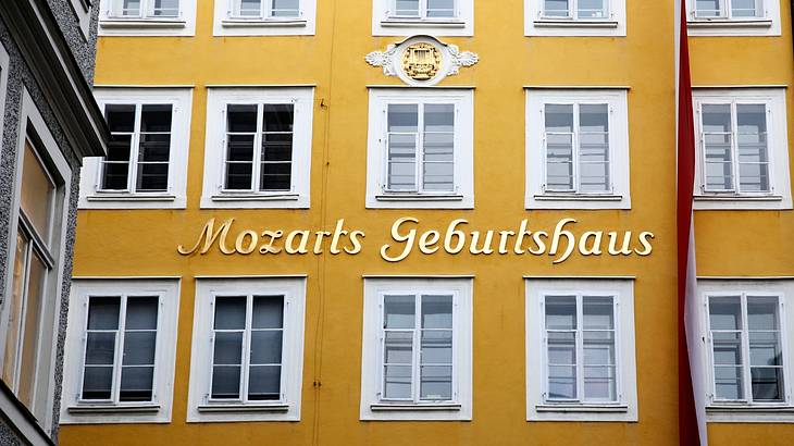 A yellow building with white windows and a sign that says "Mozart's Geburtshaus"