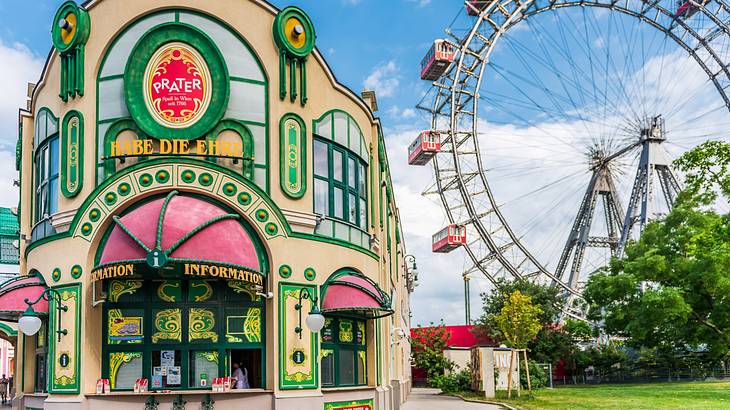 A colourful building that says "Prater" next to a Ferris wheel and trees