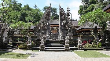 A temple with stone carvings next to a path and green trees on a clear day