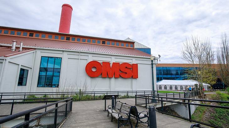 A white building with a red chimney and a red OMSI sign