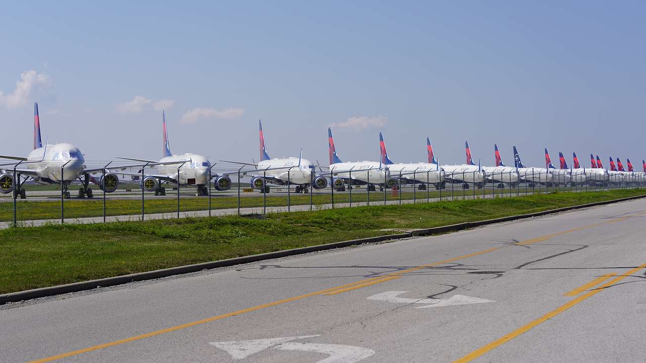 A runway with parked planes lined up against a grass verge