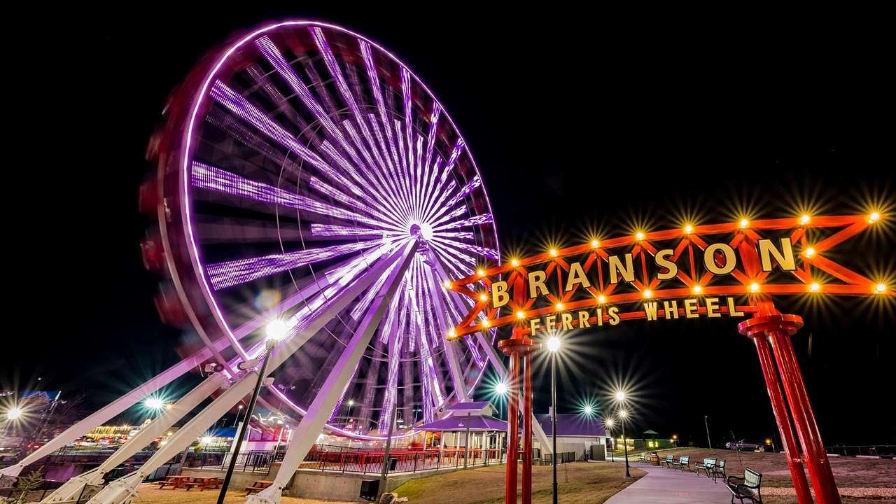 A Ferris Wheel lit pink at night with a neon sign that says "Branson Ferris Wheel"