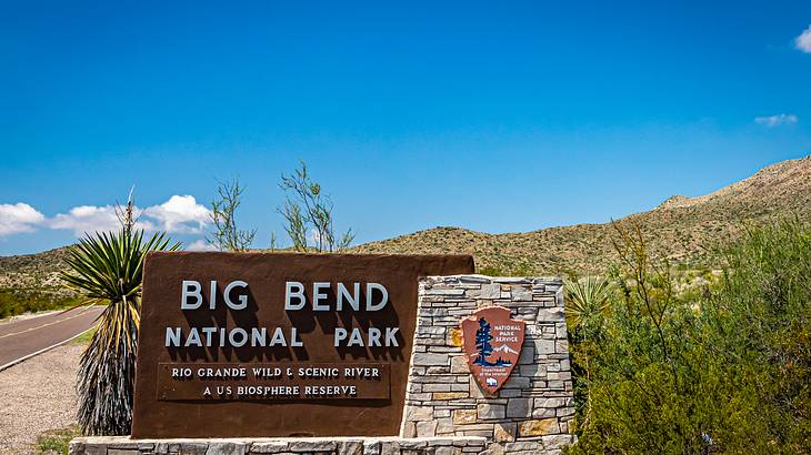 A sign that says "Big Bend National Park" within greenery and a sandy path