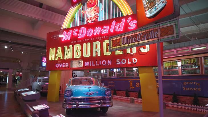 A museum exhibit with a vintage car and retro neon Mcdonald's sign