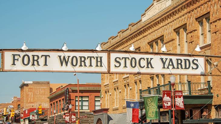 A sign that says "Fort Worth Stockyards" next to a brick building with banners