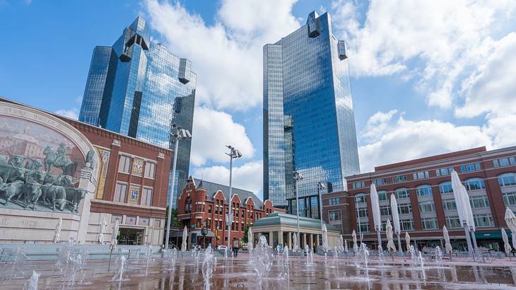 A square with fountains next to mirrored skyscrapers and red brick buildings A square with fountains next to mirrored skyscrapers and red brick buildings