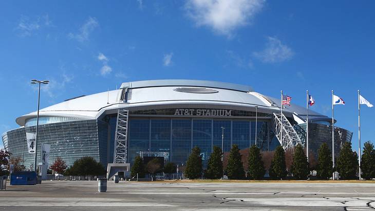 A football-shaped arena that says "AT&T Stadium" next to flags and a road