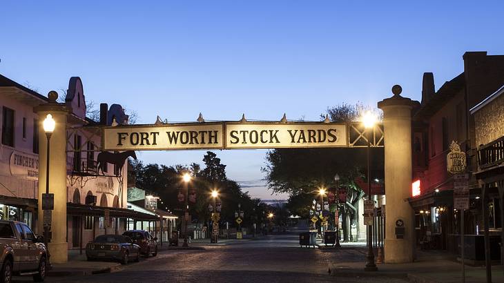 A sign across a road that says "Fort Worth Stock Yards" at night with street lights A sign across a road that says "Fort Worth Stock Yards" at night with street lights