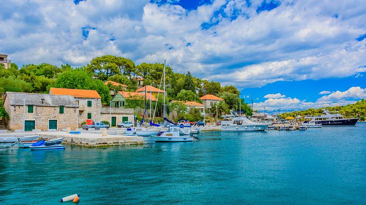 A body of water with boats next to trees and small stone houses