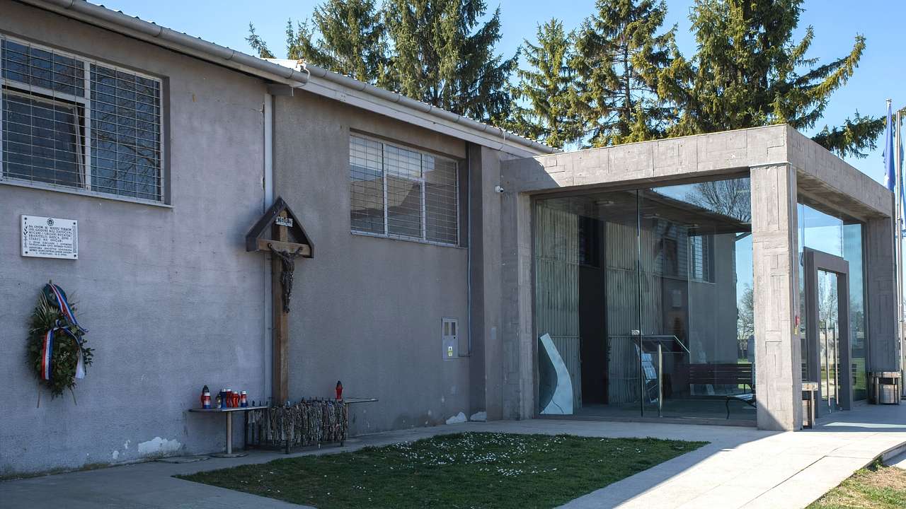 A grey stone building with a glass door and a small memorial