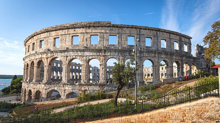 A circular stone amphitheatre with trees and grass around it