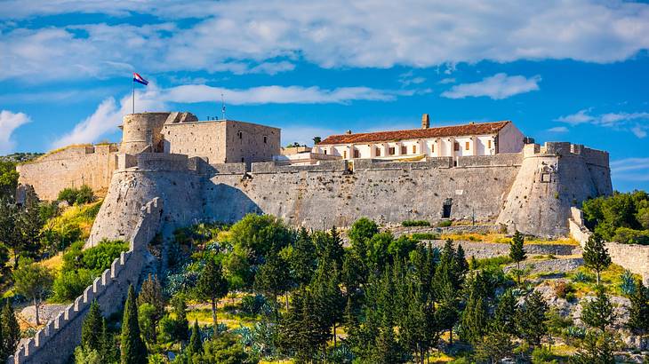 A stone fortress on a cliff under a blue sky with clouds