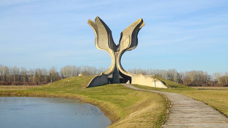 A large stone structure next to a body of water and the grass