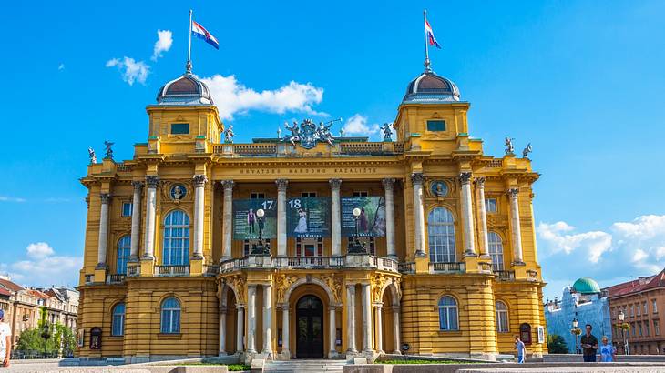 A large yellow theatre building with flags atop it