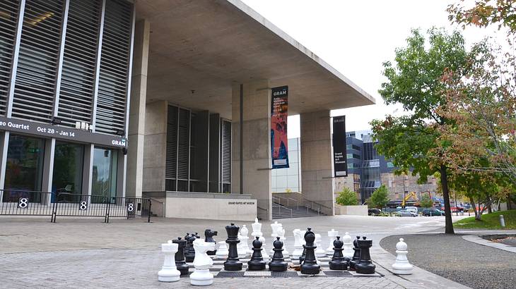 A modern concrete museum building with a giant chess set in front