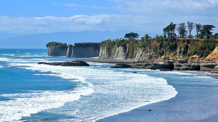 A bay of water surrounded by high cliffs and clouds above