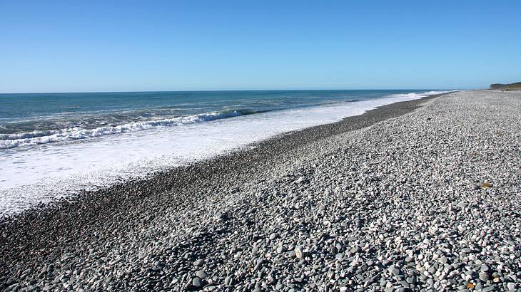 A rocky beach with waves lapping the shore on a clear day