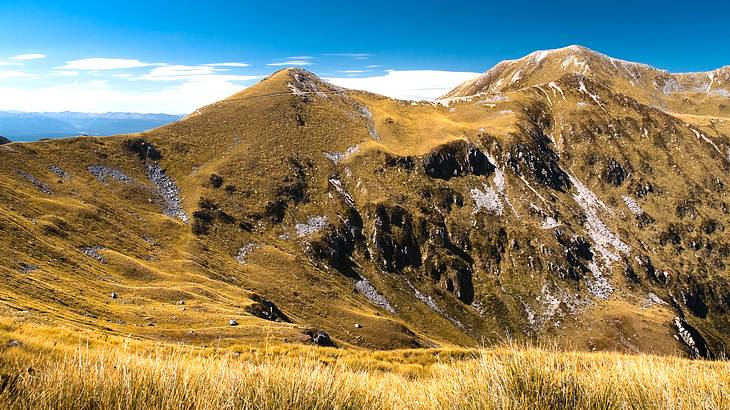 A hiking track going up a mountainside with several mountain ranges at the back