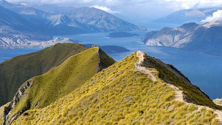 A mountain peak overlooking blue water and other mountain ranges