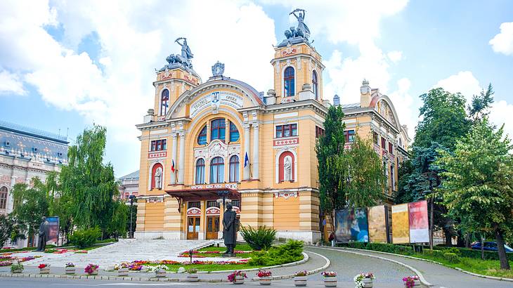 A view of a yellow theatre building and partially cloudy sky, Cluj-Napoca, Romania