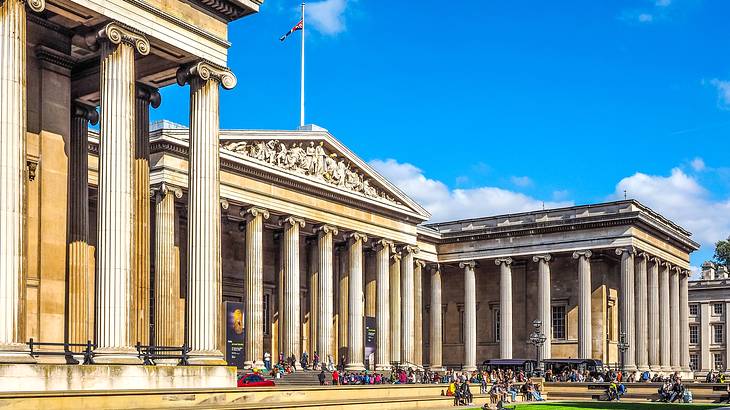 Outside facade of British Museum with tall columns and green grass in front, London