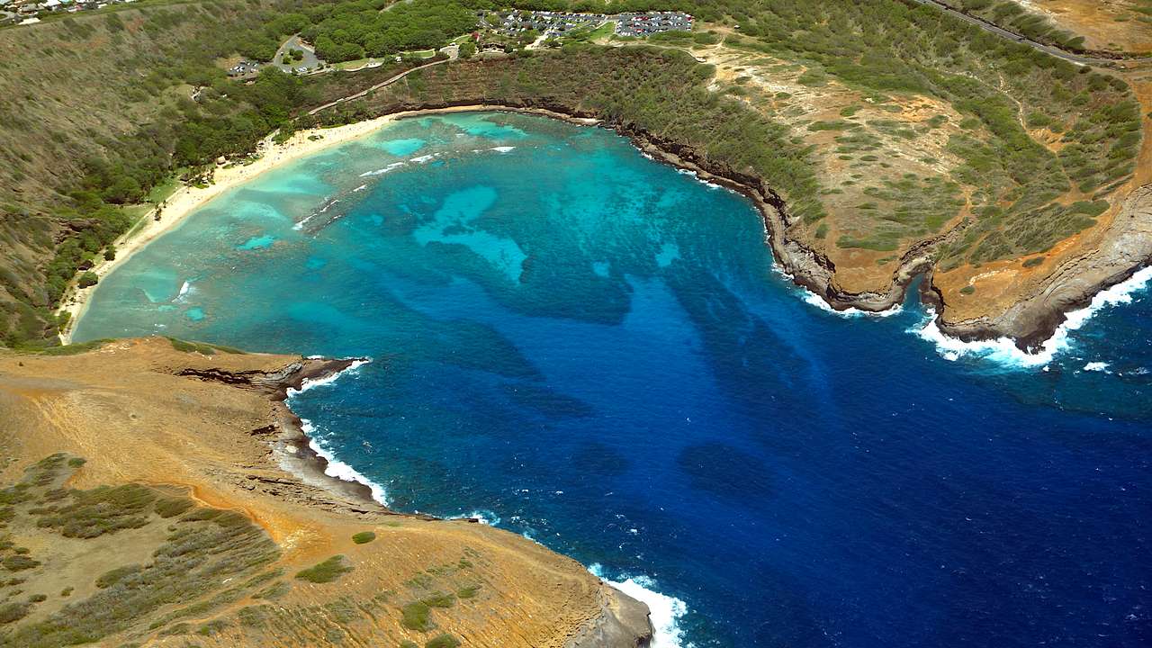 A turquoise-colored bay and white sand beach taken from a high angle