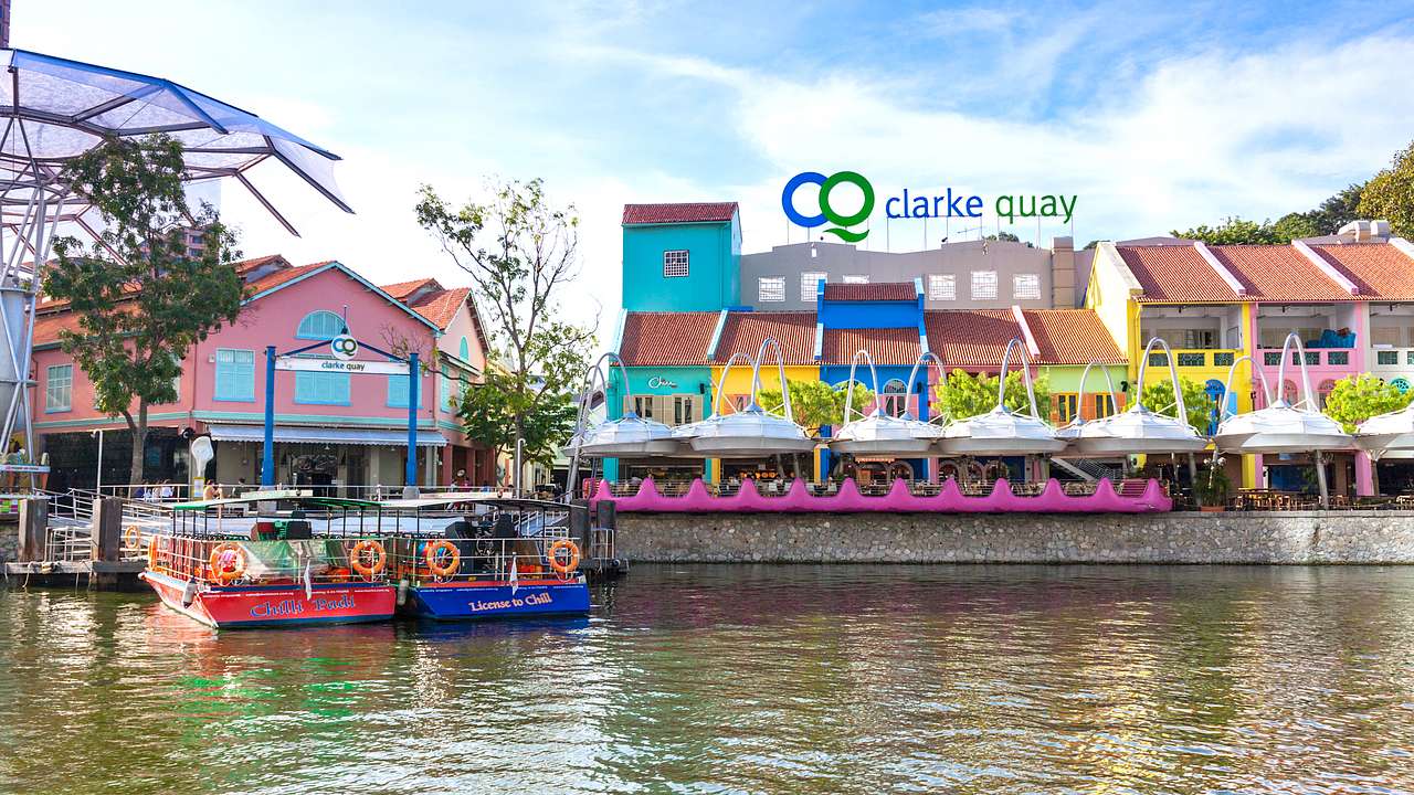 Colourful buildings, a walkway over water and a boat in Clark Quay, Singapore