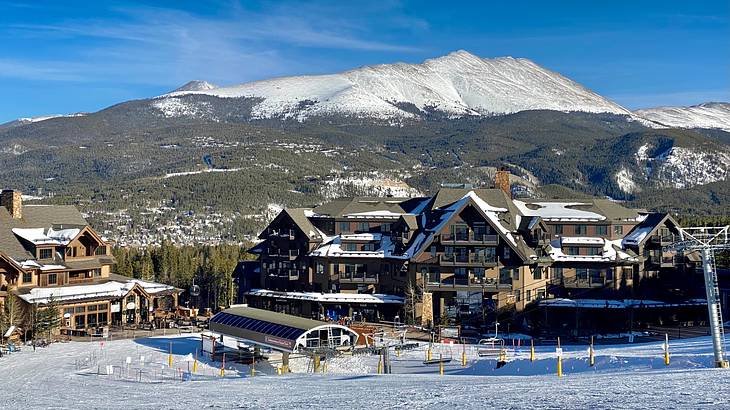 Ski lodges on snowy ground with a snow-covered mountain in the background