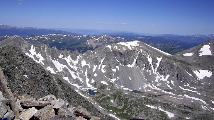 Partially snow-covered mountain range with sparse greenery at its base