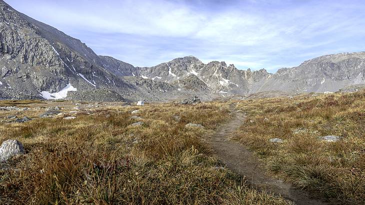 A dirt road through a grassy landscape leading to a mountain range